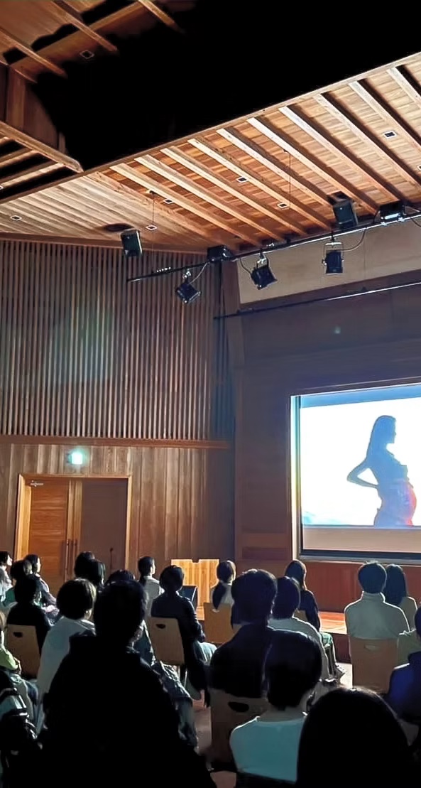 People watching a film in a hall with a wooden ceiling
